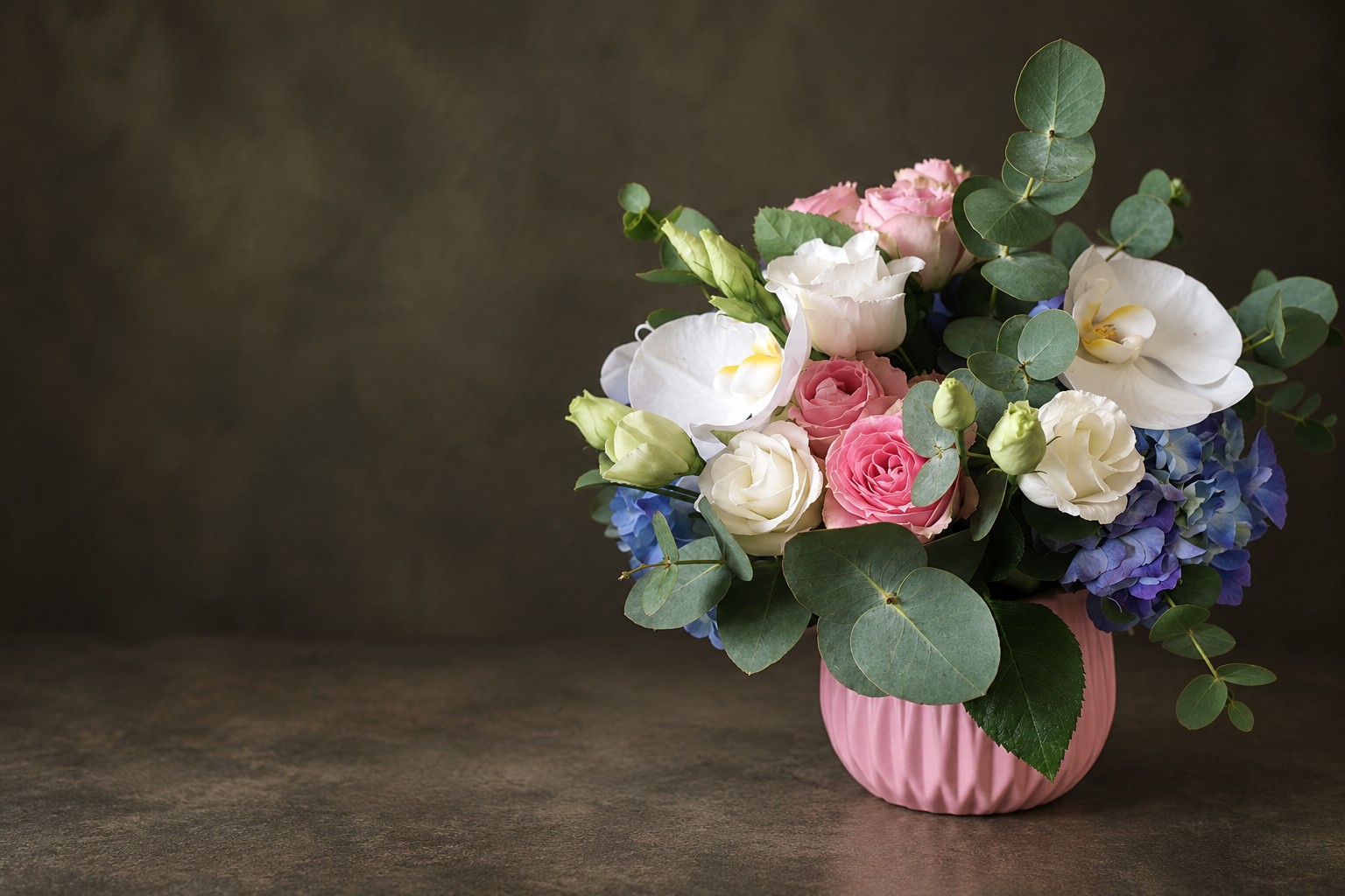 Composition pastel de la boutique dans son pot rose, avec roses, orchidées, hortensias et eucalyptus