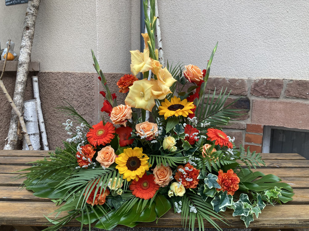Composition florale orange et jaune sur table en bois